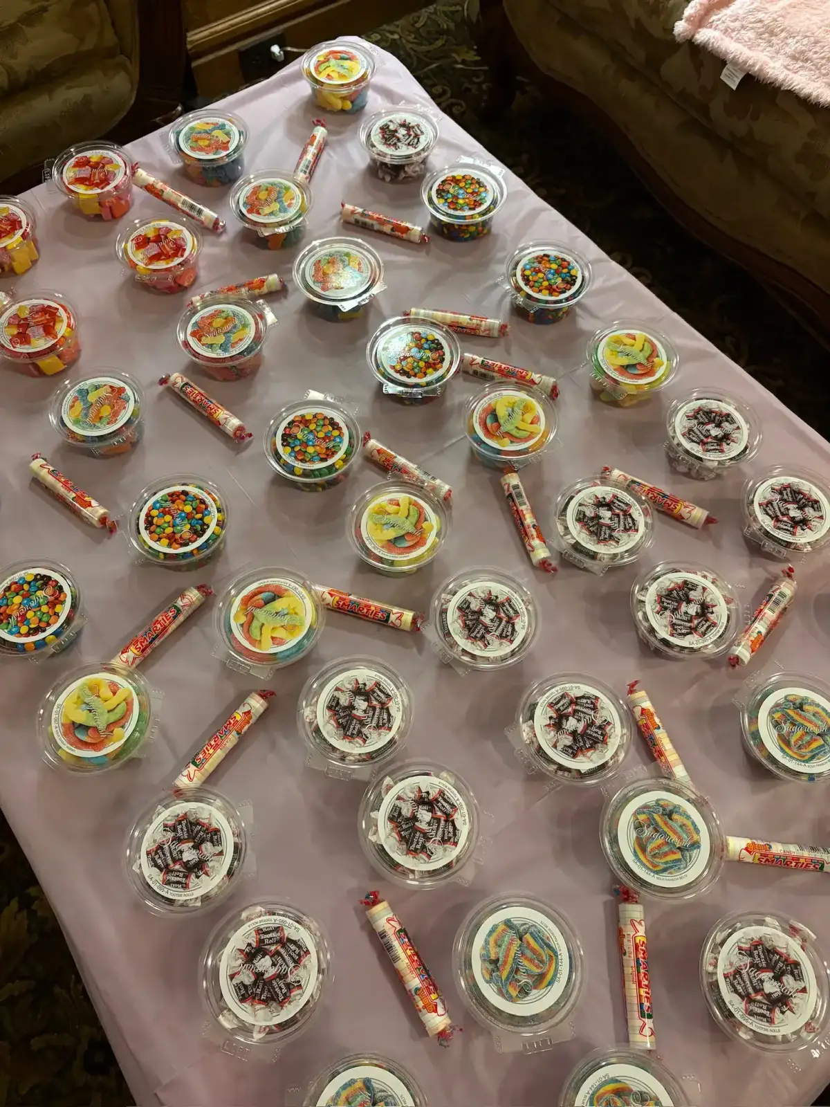 Rows of Sugarwish candy cups and candy rolls laid out on a table in the Clue candy room