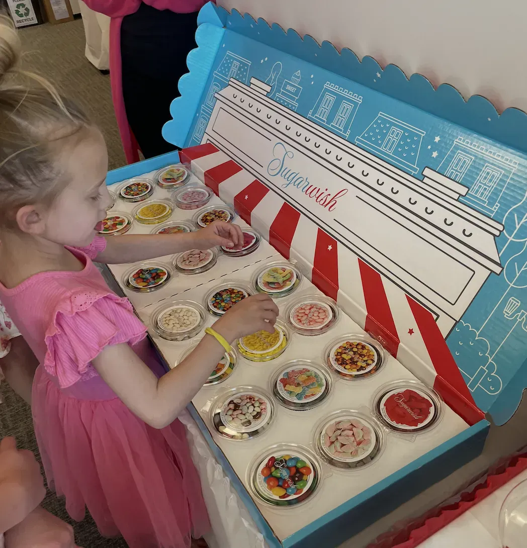 Make-A-Wish child picking out her favorite Sugarwish candy treats from a giant display box