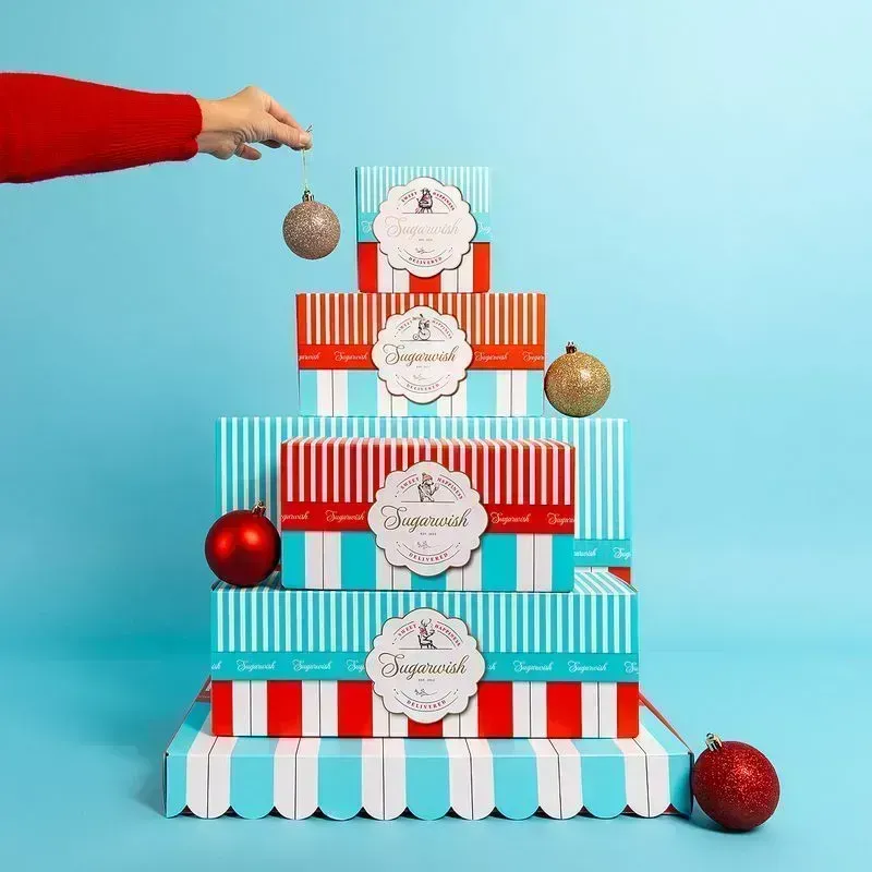 Sugarwish holiday gift boxes stacked in a Christmas tree shape on a teal background