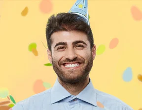 smiling man wearing a birthday party hat