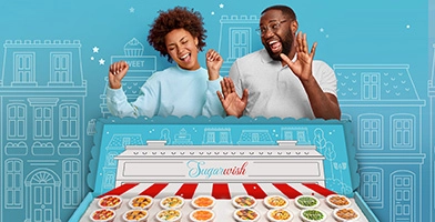 Two people dancing around a Sugarwish party gift box full of candy